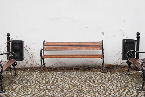 istock Bench against white wall on cobblestone street 468986352