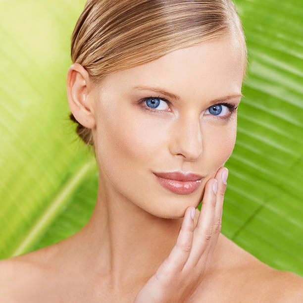 Portrait of all natural beauty A beautiful young woman touching her face with a green leaf in the background pale complexion stock pictures, royalty-free photos & images