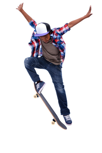 An African-American boy doing a trick on his skateboard