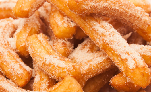 Detail of a pile of newly made Spanish churros.  typical pastry mexican breakfast dessert eaten with hot chocolate, lemon cream, sugar and cinnamon, caramel