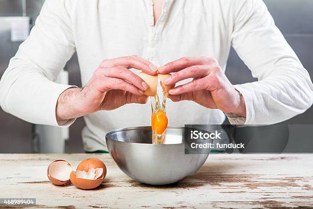 Cook Breaking An Egg In To The Bowl Stock Photo - Download Image Now - Animal Shell, Breaking, Indoors