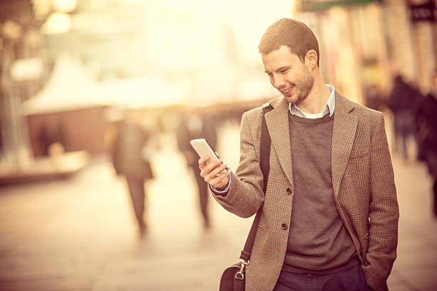 istock Smiling man using a smartphone on the street 468992669