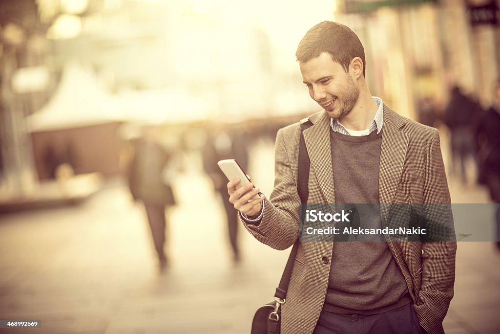 Smiling man using a smartphone on the street 25-29 Years Stock Photo