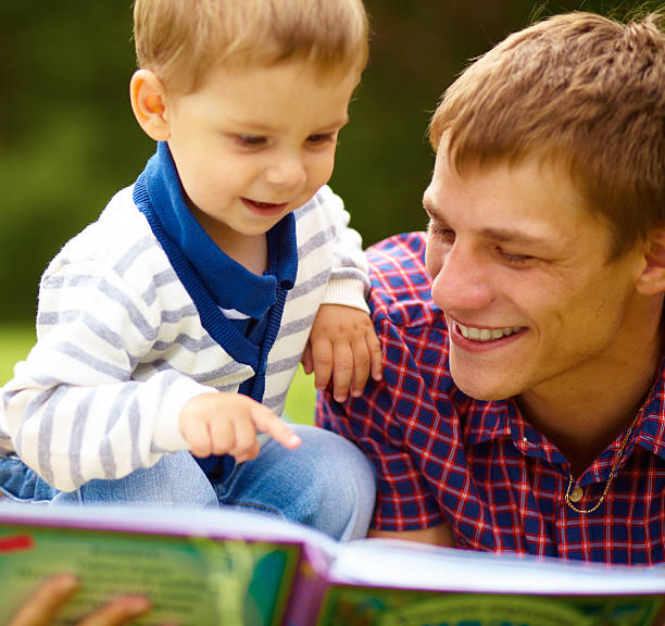 istock dad and little boy reading a book on the meadow 468992799
