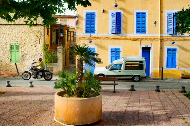 Man riding a motorcycle in Panier Marseille France Marseille, France - May 22, 2014: A man riding a motorcycle in the square called “Place des Moulins” in the historical Panier district. Blue and green window shutters are seen in the background buildings. marseille panier stock pictures, royalty-free photos & images