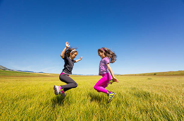 istock Happy young girls jumping on a meadow 468993154
