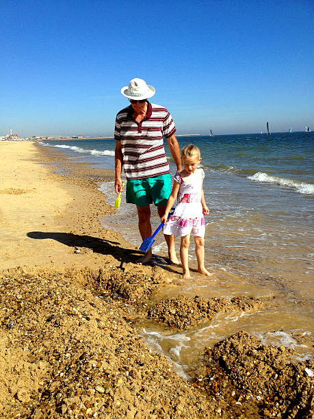 grand-père et dranddaughter sur la plage - sandcastle beach norfolk sand photos et images de collection