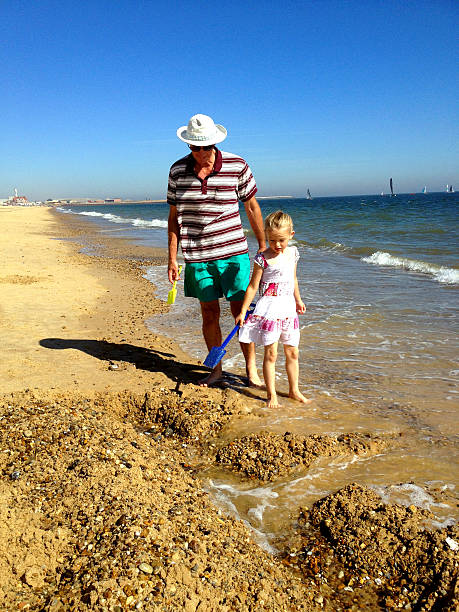 nonno e dranddaughter sulla spiaggia - sandcastle beach norfolk sand foto e immagini stock