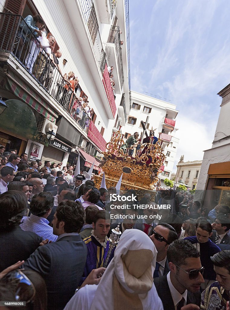 Holy Week celebrations in Seville Sevilla, Spain - April 4, 2009: Jesus Christ float and procession (brotherhood of La Paz) during the Holy Week surrounded by hundreds of believers while walking thru the streets of Seville closing to Arco del Postigo one of the most important points of the procession. This brotherhood is followed by 1200 official penitents that walks around the city for many hours on Palm Sunday. Catholicism Stock Photo