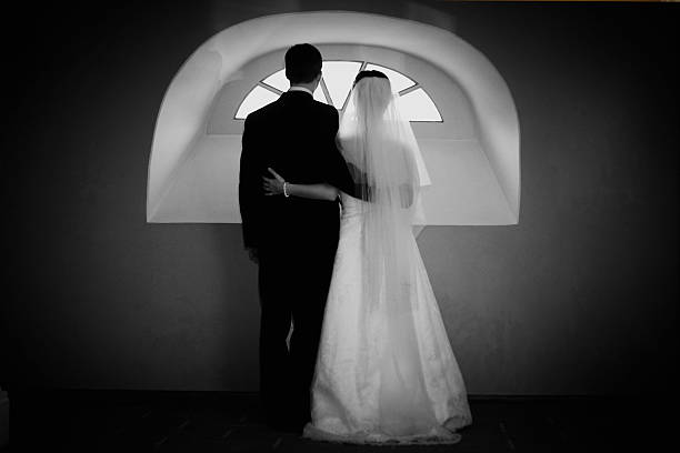 Bride standing at the window with his back to the camera, his face is not visible