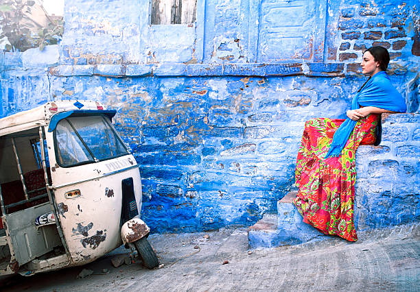 Image of a straw roof home in southern India. Beautiful colors with a vintage scooter and laundry hanging in front of the building.
