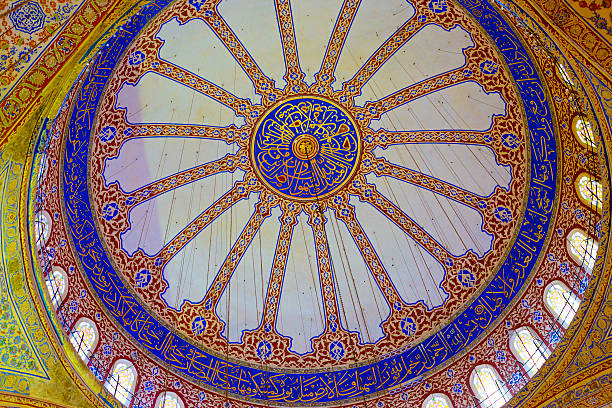 Sultan Ahmed Mosque or Blue Mosque or Sultan Ahmet Camii in Turkish in Istanbul Turkey. Upwards view of the richly decorated dome roof inside the mosque.