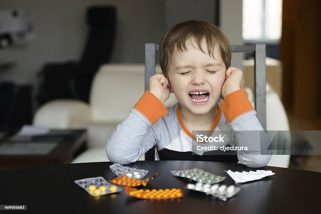 4 year old boy crying before swallowing medication 4 year old boy crying before swallowing medication at home Ear Stock Photo