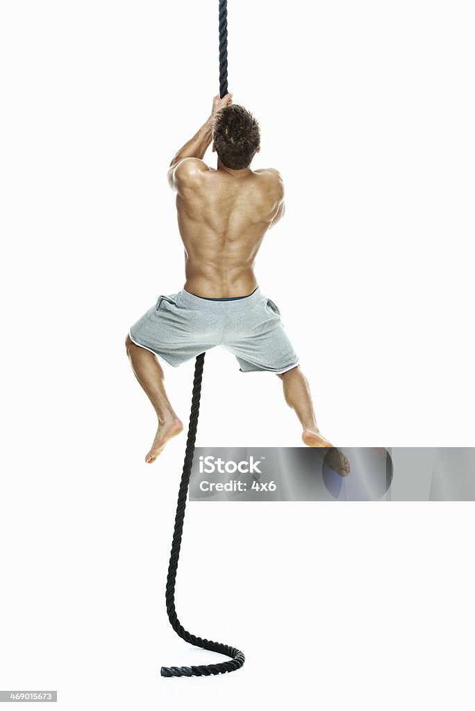 Rear View Of Man Climbing A Rope Stock Photo - Download Image Now