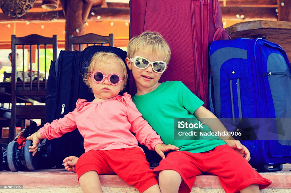 Boy and toddler girl with sunglasses sitting by suitcases little boy and toddler girl sitting on suitcases ready to travel, kids travel 2015 Stock Photo