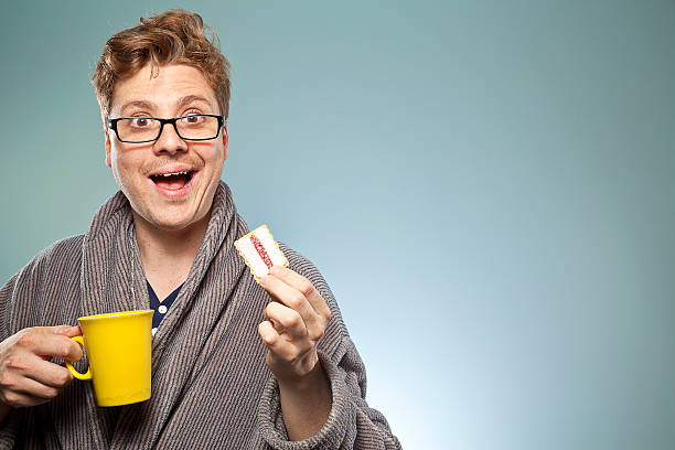 istock Nerdy guy smiling with a coffee and biscuit 469024998
