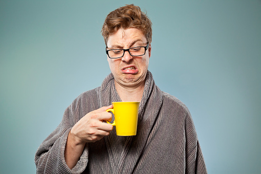 Nerdy guy looking like he's just taken a sip of really bad tea or coffee in the early hours of the morning. He's wearing a dressing gown and is still in his pyjamas having just gotten out of bed. Is that coffee any good?