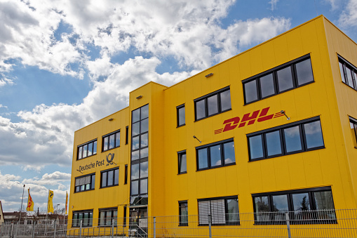 Fuerth, Germany - April 6, 2015: A yellow business building of DHL and Deutsche Post in Germany at daylight. The building belongs to a distributor center of the DHL and Deutsche Post Group. DHL is part of Deutsche Post providing international mail services.