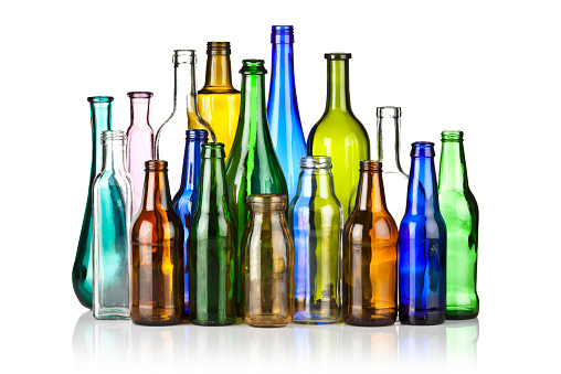 Large assortment of multicolored glass bottles on reflective white backdrop