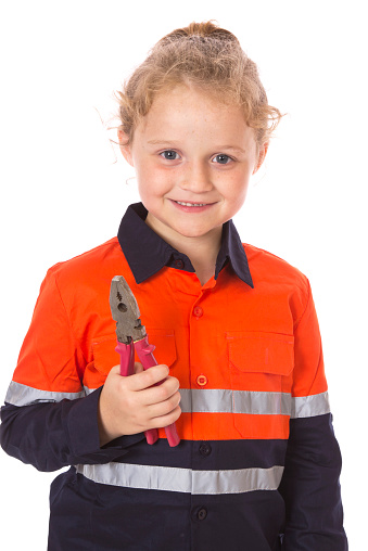 A little girl wearing high visibility, orange work clothes holding a pair of pliers. Promoting gender equality in the work force. Encouraging young girls to head into the trades. Isolated on white.