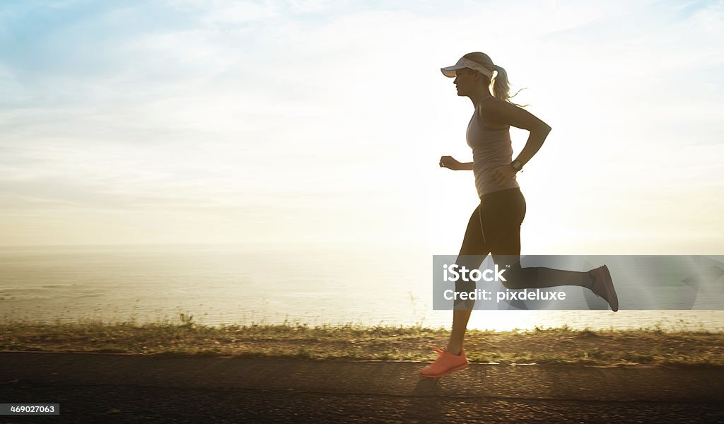 Enjoying her early evening run Side view of a young woman running along a coastal road with the sun setting behind herhttp://195.154.178.81/DATA/i_collage/pu/shoots/784359.jpg Beach Stock Photo