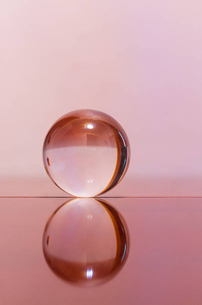 istock Glass transparent ball on light pink background and mirror surface 469032636