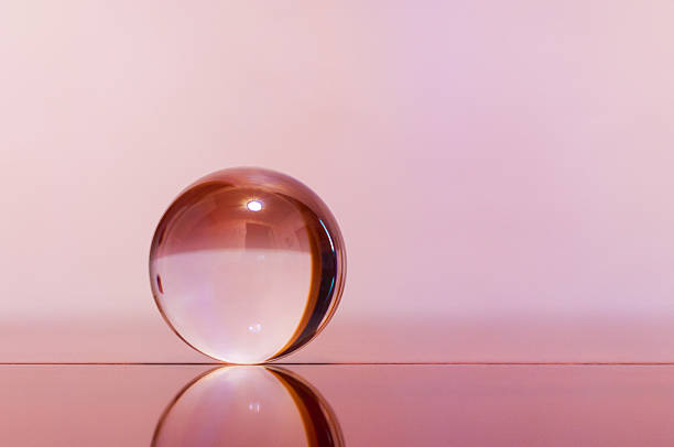 istock Glass transparent ball on light pink background and mirror surface 469032638