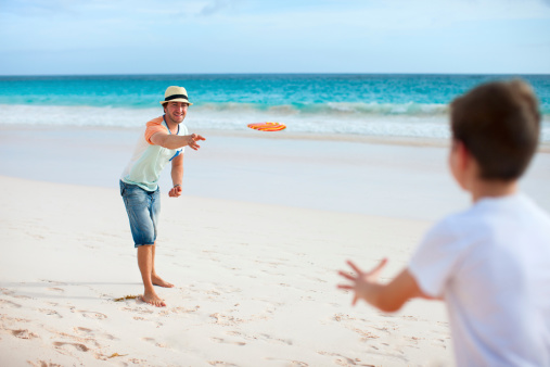 Father and son playing frisbee at beach