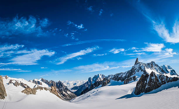 Alps snowy mountain valley dramatic rocky peaks panorama blue sky High altitude panoramic view above the clouds across the bright white glaciers, dramatic rocky pinnacles and high altitude summits of the Mont Blanc Massif and the Vallee Blanche from the Pointe Helbronner in Italy past the iconic Alpine peaks of the Aiguille du Midi to the Aiguille Verte and Les Drus, and down the Glacier du Geant down to the Chamonix valley in France. ProPhoto RGB profile for maximum color fidelity and gamut. aiguille de midi photos stock pictures, royalty-free photos & images