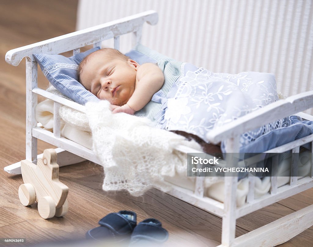 newborn baby  in a small bed newborn boy sleeps in a small bed. nearby is a toy boat 0-11 Months Stock Photo