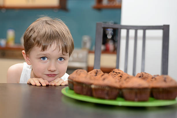 istock 4 year old boy hungrily looking at chocolate cake 469044117