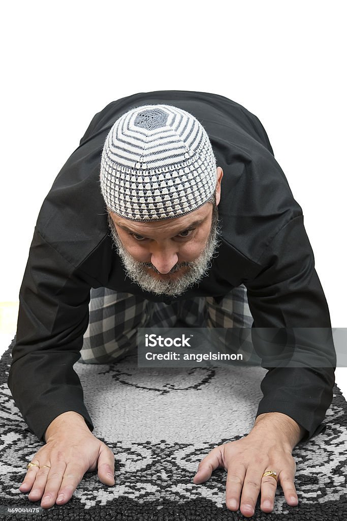 Muslim man praying. Muslim man in traditional dress praying over a white background. Adult Stock Photo