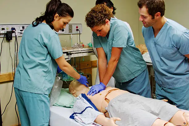 Medical staff practice CPR on mannequin