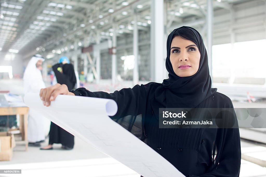 Project is coming together Arabic businesswoman is looking at blueprints and her construction project. Women Stock Photo
