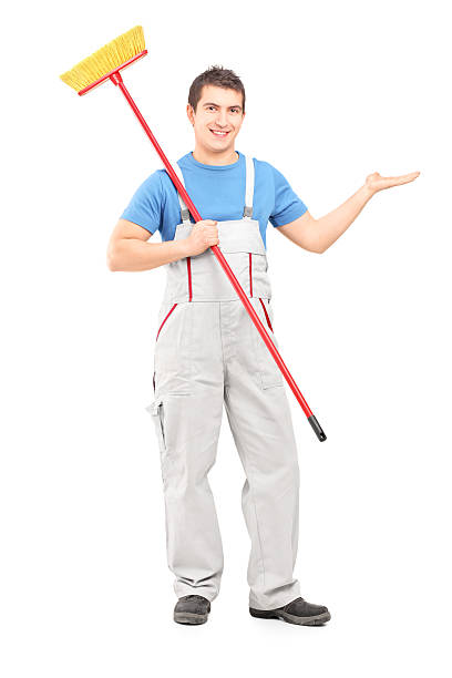 istock Cleaner in uniform with a broom pointing 469048869