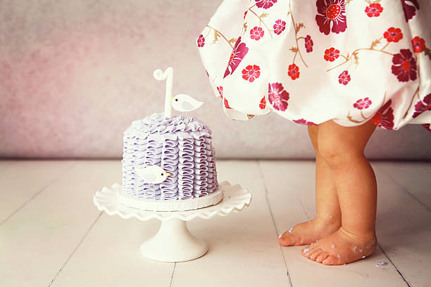 A cropped image of a baby girl standing beside her first birthday cake. Shot with a Canon 5D Mark II. Some copy space.