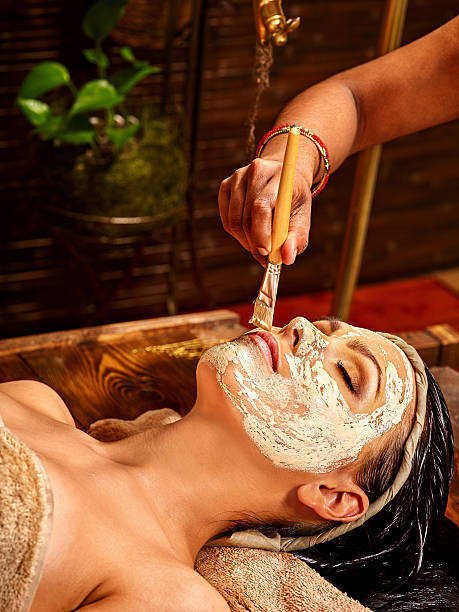 A woman laying down in towel wearing mask at Ayurveda spa stock photo