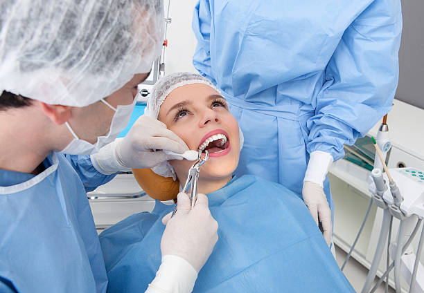 istock Dentist holding dental instruments in young woman's mouth 469056674