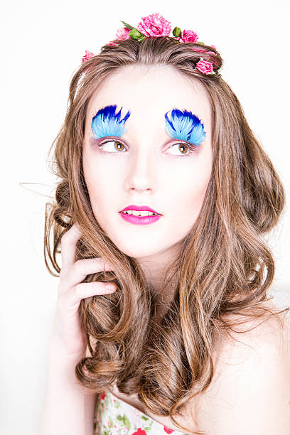 Beautiful girl with creative make-up and hairstyle with flowers Portrait of a beautiful young woman on a white background. Girl with creative make-up and hairstyle with flowers clump eyelashes stock pictures, royalty-free photos & images