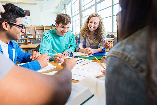 istock Diverse high school students studying for exam together in library 469062400