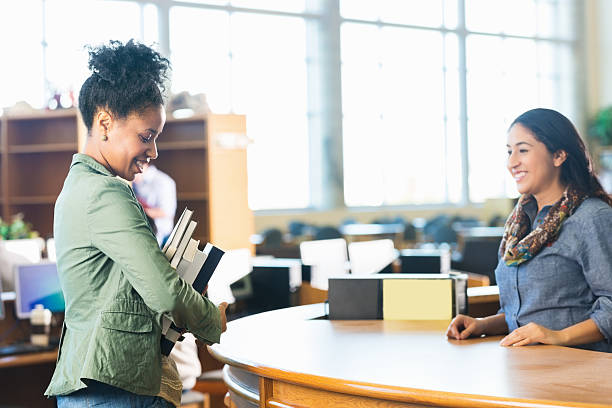 istock Adult college student is holding stack of books in library 469062490