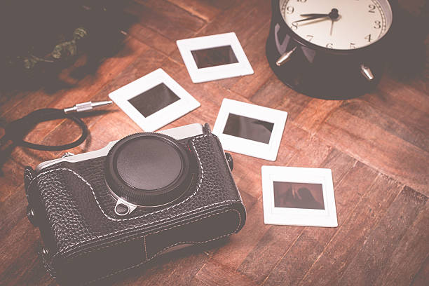 istock retro camera, slide film frame & clock on wood floor 469069440