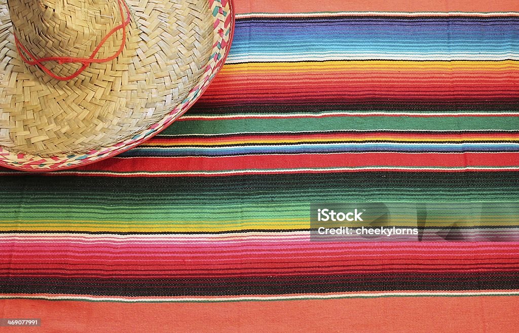 Mexico fiesta poncho serape rug blanket sombrero background copy-space Traditional Mexican fiesta poncho rug in bright colours with sombrero background with copy space Blanket Stock Photo