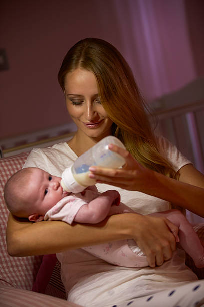 istock Mother Feeding Baby With Bottle In Nursery 469081682