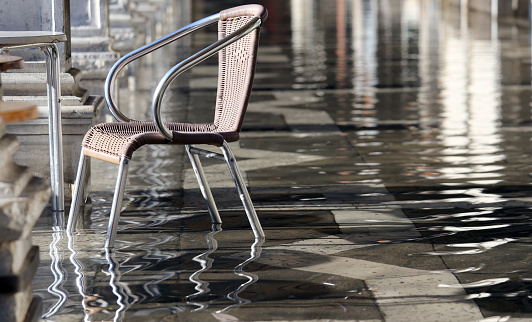 single chair at high tide under the arcades during the flood in Venice in Italy