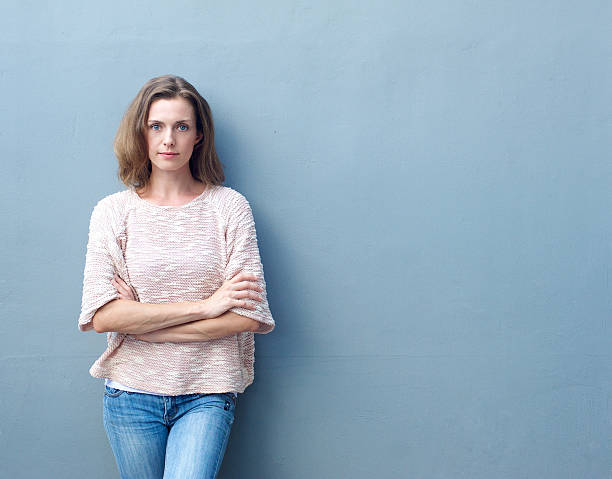 confiante de meados adulto mulher posando com braços cruzados - blank expression imagens e fotografias de stock