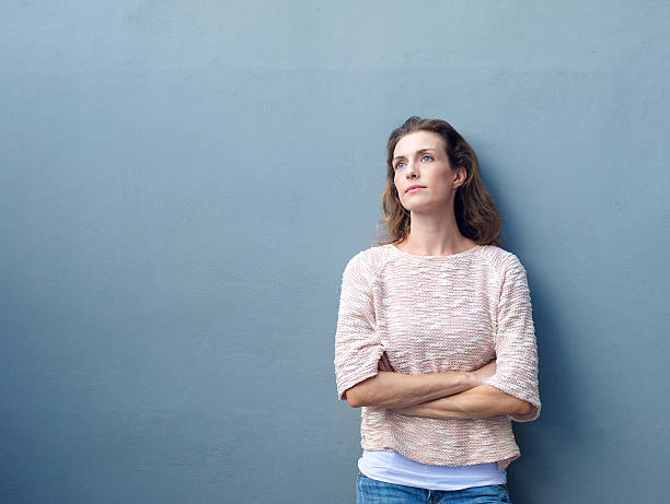 istock Woman with arms crossed looking away with thoughtful expression 469084860