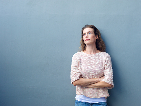 Portrait of an attractive woman posing with arms crossed looking away with thoughtful expression