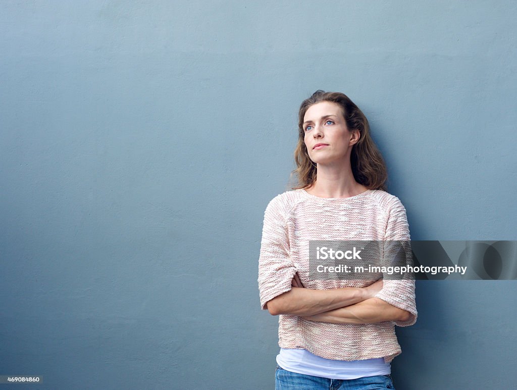 Woman with arms crossed looking away with thoughtful expression Portrait of an attractive woman posing with arms crossed looking away with thoughtful expression Women Stock Photo