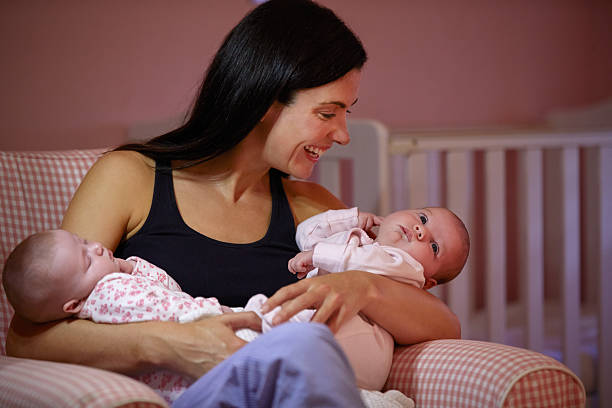 mãe em casa cuddling filhas de bebê no berçário de solteiro - sibling baby three people baby girls - fotografias e filmes do acervo